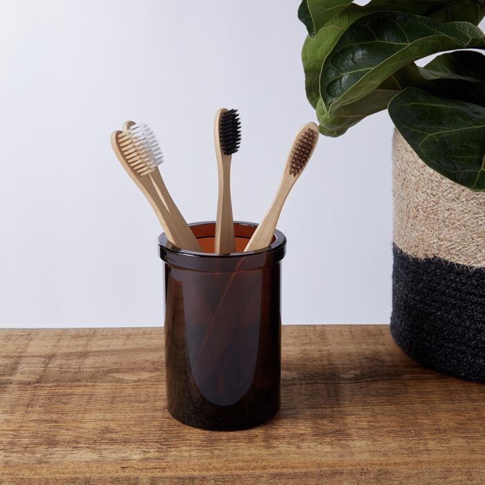 Amber glass toothbrush holder with bamboo toothbrushes for a plastic-free bathroom